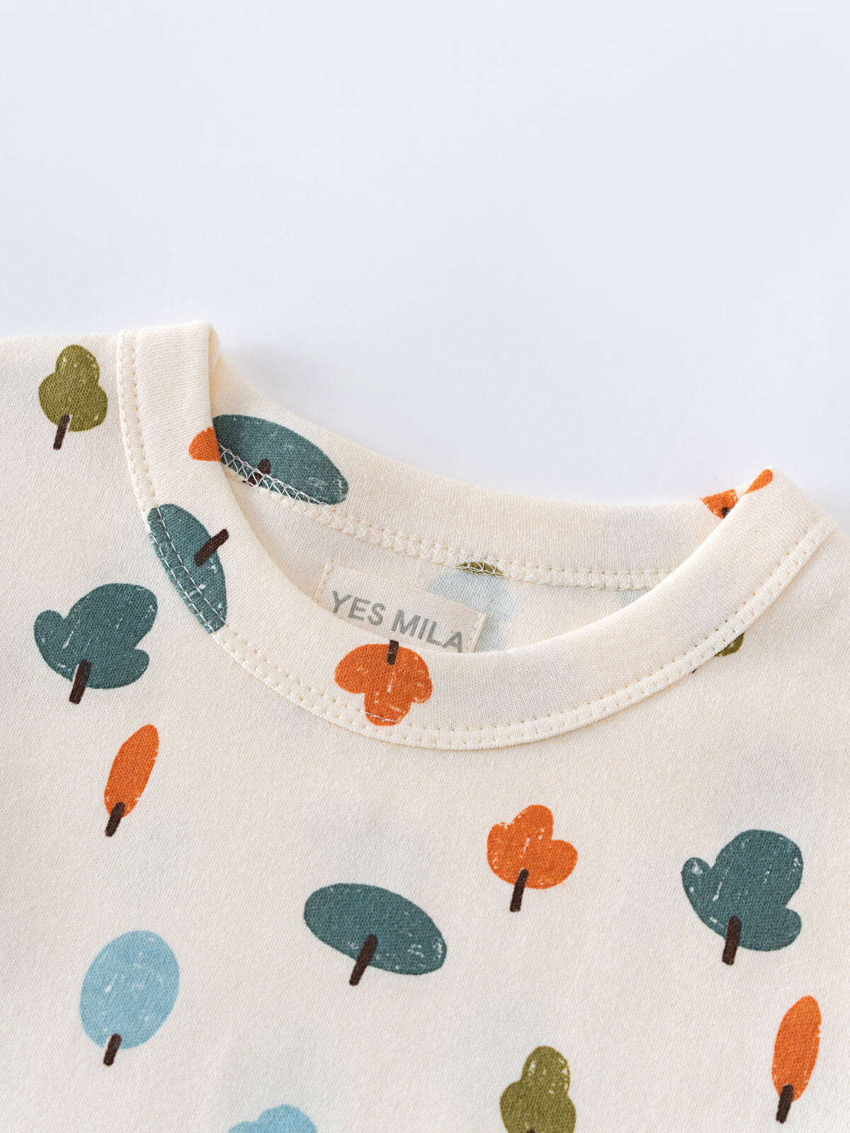 Close-up of cream-colored shirt collar with printed tree pattern in orange and teal Printed Short Sleeve Tee - Forest Adventure Ecru Boys