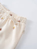 Close-up of cream-colored sweatpants waistband with small printed faces pattern Printed Sweatpants - Little Acorn Ecru Baby girl