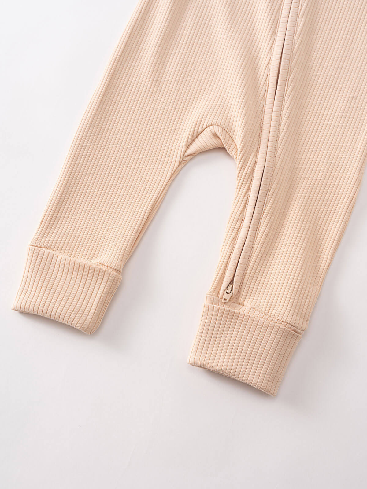 Close-up of ribbed fabric sleeves with cuffs and zipper detail in beige Ribbed Long Sleeve One Piece - Clay Baby girl