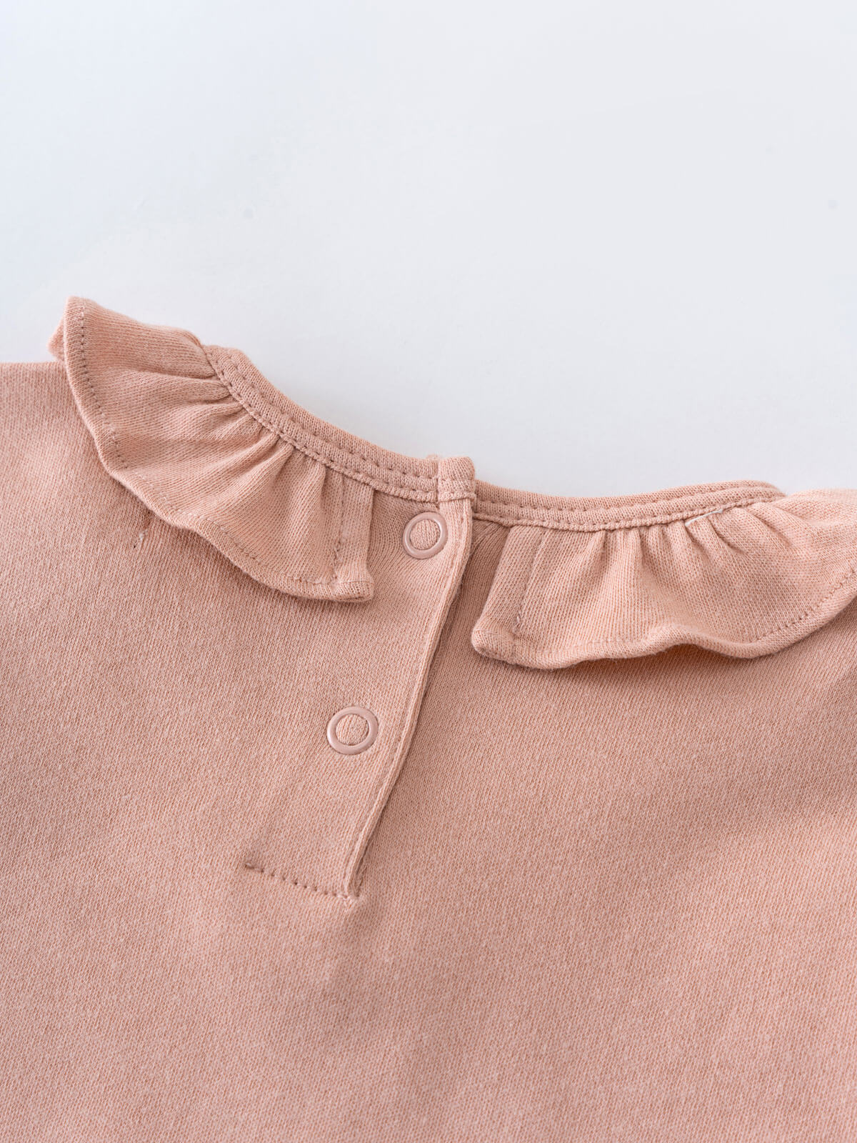Close-up of a blush pink knit collar with ruffle detail and buttons Ruffle Long Sleeve Bodysuit - Blush Baby girl