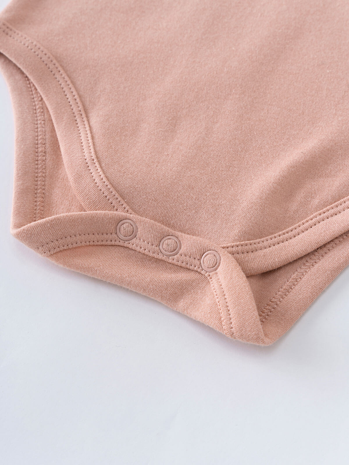 Close-up of a blush pink baby bodysuit with three snap closures Ruffle Long Sleeve Bodysuit - Blush Baby girl
