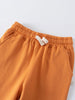 Close-up of orange sweatpants with elastic waistband and white drawstring detail Sweatpants - Pumpkin Boys