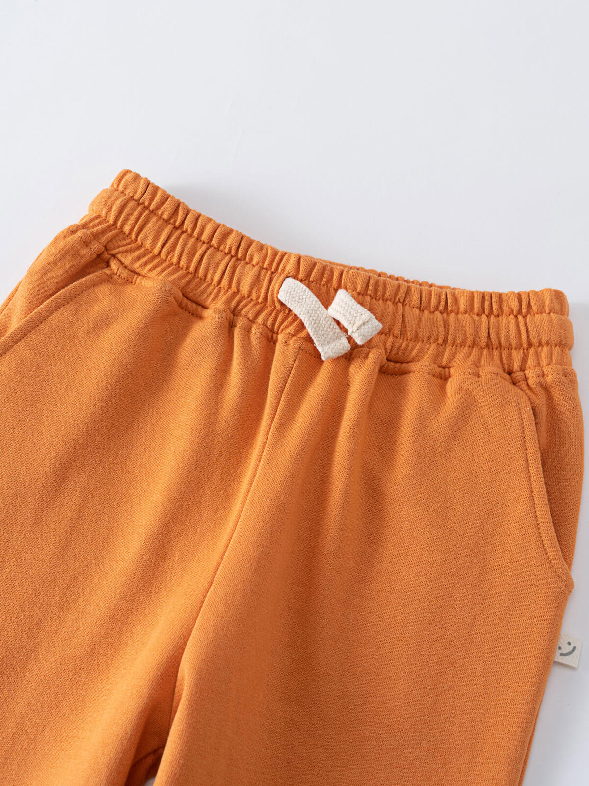Close-up of orange sweatpants with elastic waistband and white drawstring detail Sweatpants - Pumpkin Boys