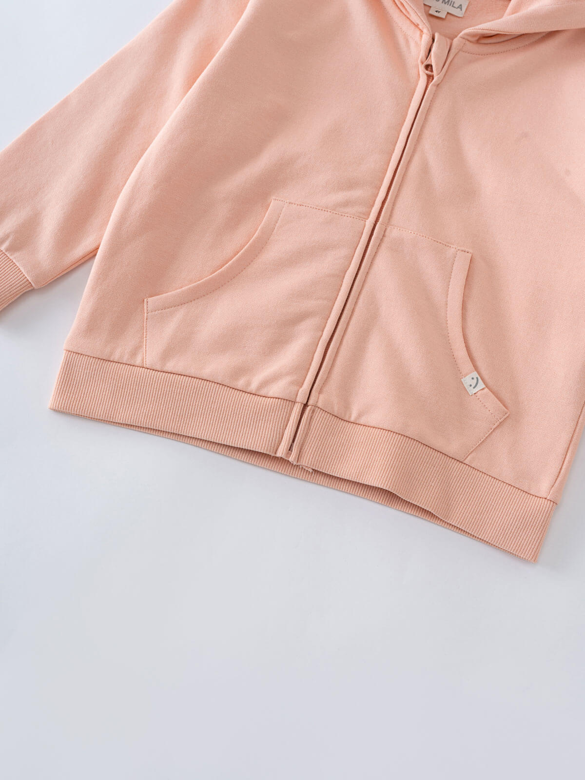 Close-up of a peach-colored zip hoodie showing pockets and ribbed hem Zip Hoodie - Mallow Boys
