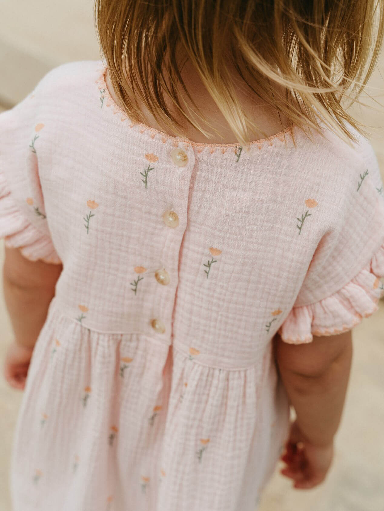 Close-up of a child wearing a pink dress with floral embroidery on a neutral background Amara Dress - Poppy Field Girls
