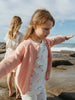Two young girls on a rocky beach with ocean view