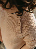 Close-up of a beige knitted sweater with buttons