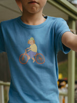 Child wearing a blue t-shirt with a graphic of a person on a bicycle.