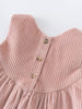 Close-up of a pink corduroy dress with buttons on a white background