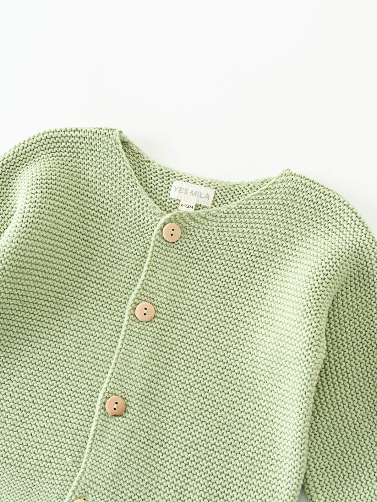 Green knitted cotton cardigan with buttons on a white background