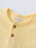 Close-up of a pale yellow henley shirt with brown buttons Baby Henley Tee - Sun Soaked Baby boy