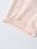 Close-up of pale pink fabric cuff with small peach-colored apple print Baby Jersey Shorts - Apples Baby girl