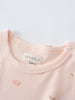 Close-up of a peach-colored baby shirt with apple print and snap button closure Baby Printed Short Sleeve Tee- Apples Baby girl