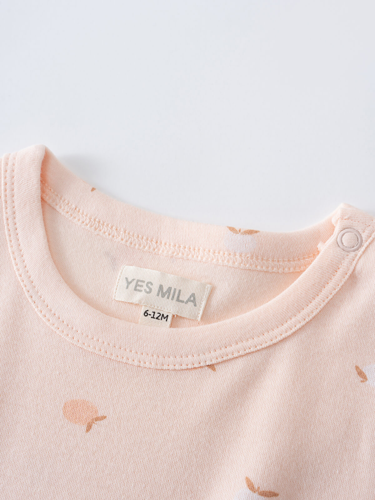 Close-up of a peach-colored baby shirt with apple print and snap button closure Baby Printed Short Sleeve Tee- Apples Baby girl