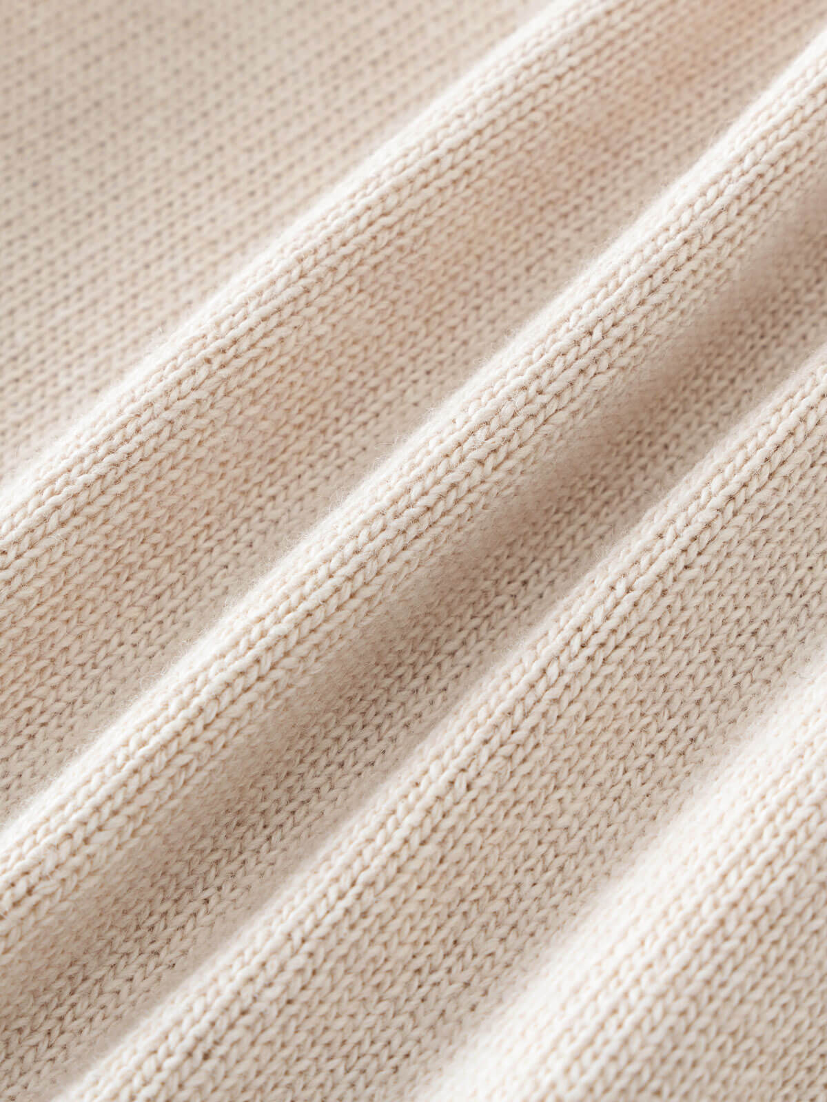 Close-up of beige fabric with a textured pattern Baby Ruffle Cardigan - Ecru Baby girl