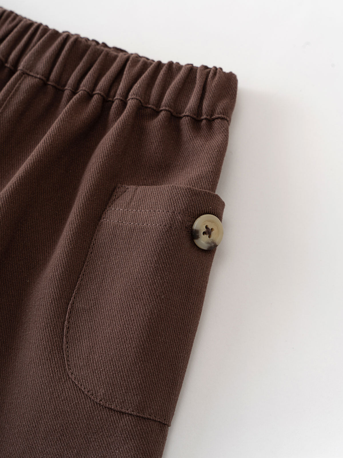 Close-up of brown twill pants showing elastic waistband and button pocket detail Baby Twill Pants - Spruce Baby boy