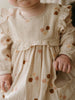Baby wearing a floral dress with a soft focus background