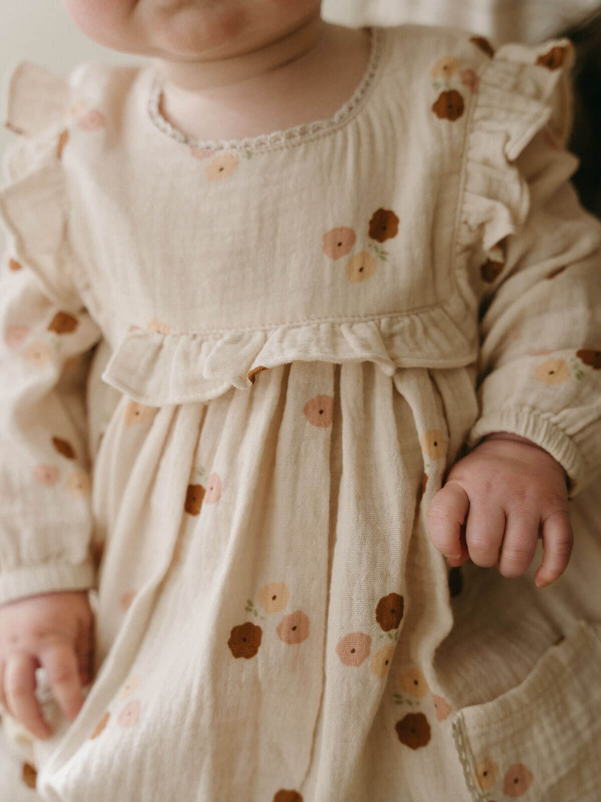 Baby wearing a floral dress with a soft focus background