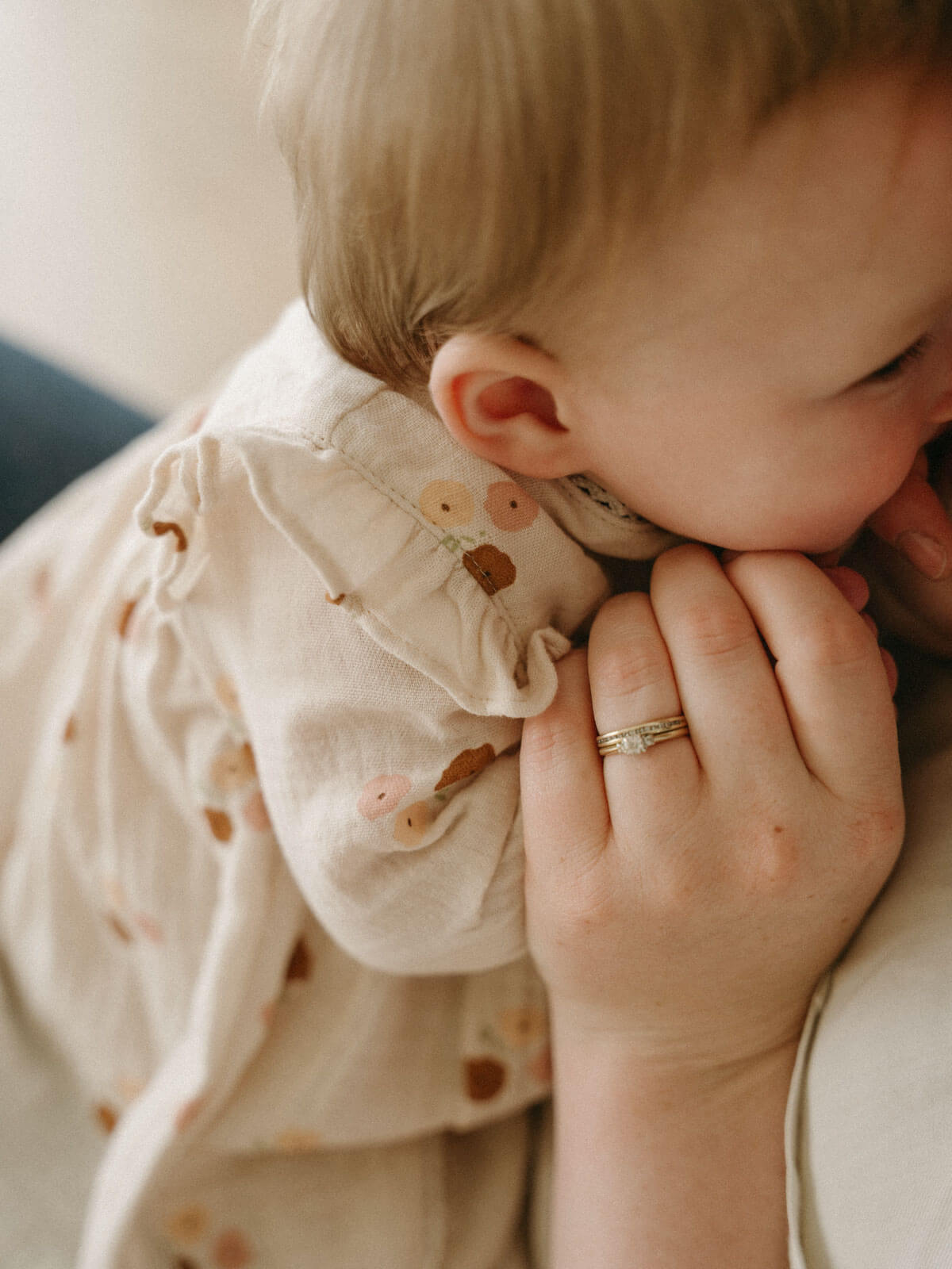 Baby being held close to a person wearing a ring, with a soft focus background