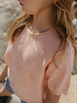 Child wearing a pink embroidered top with a blurred background