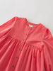 coral pink dress with button details on a light gray background