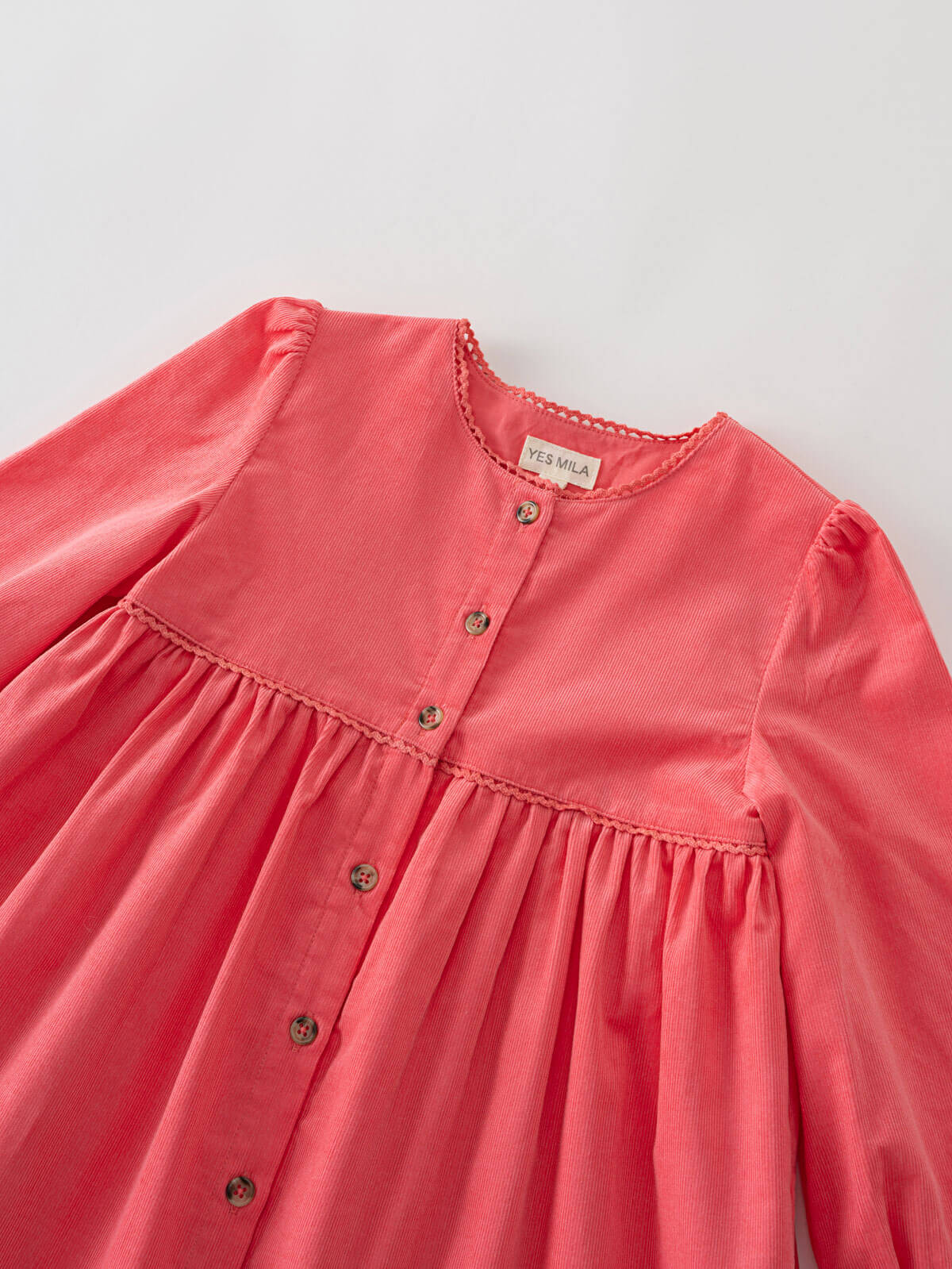 coral pink dress with button details on a light gray background