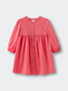 Coral pink dress with buttons on a light gray background