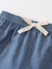 Close-up of blue chambray shorts with cream ribbon bow at waistband Chambray Shorts - Blue Chambray Baby boy