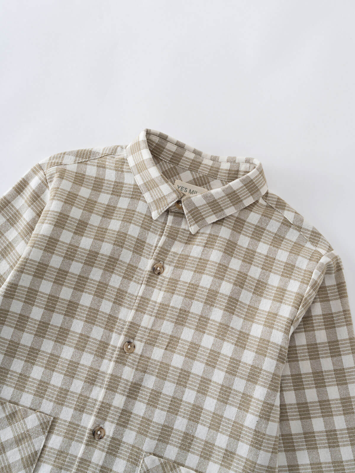 Plaid shirt with brown and white pattern on a light gray background