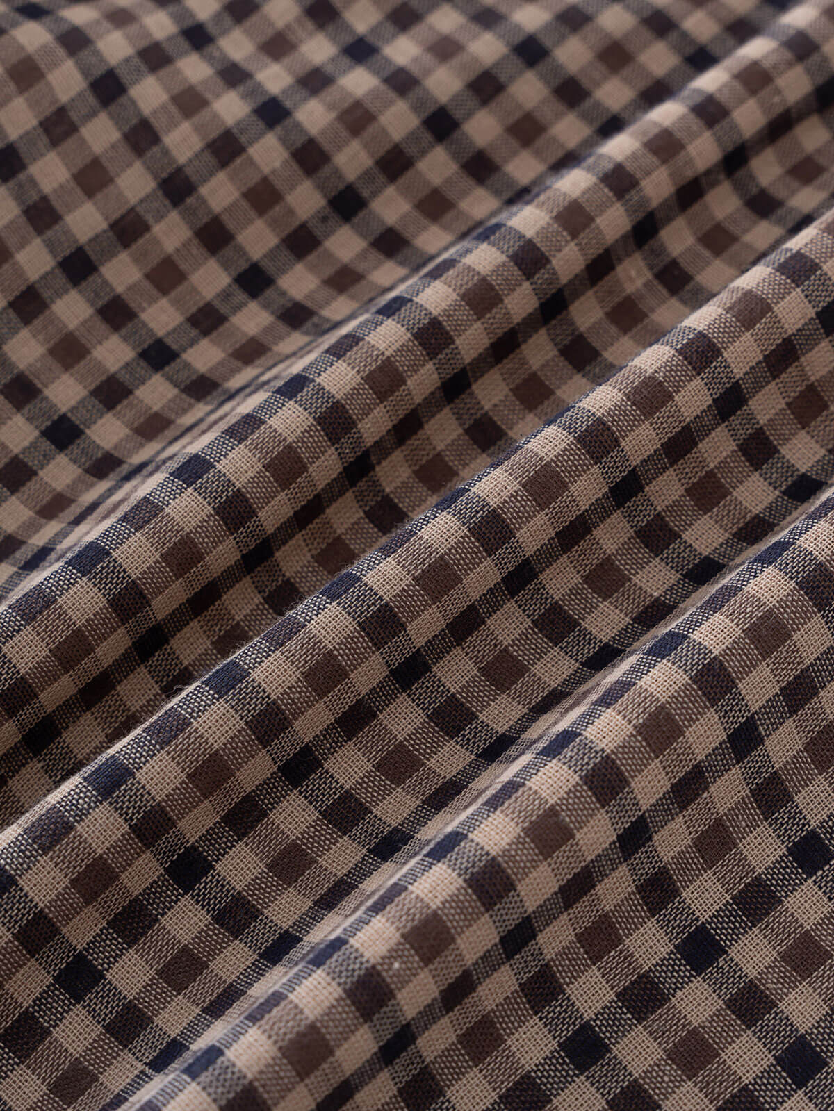 Close-up of checkered shirt fabric with brown, beige, and blue pattern