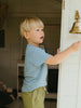 Young boy ringing a doorbell inside a house.