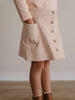 Beige corduroy skirt with button details worn by a person, on a plain background