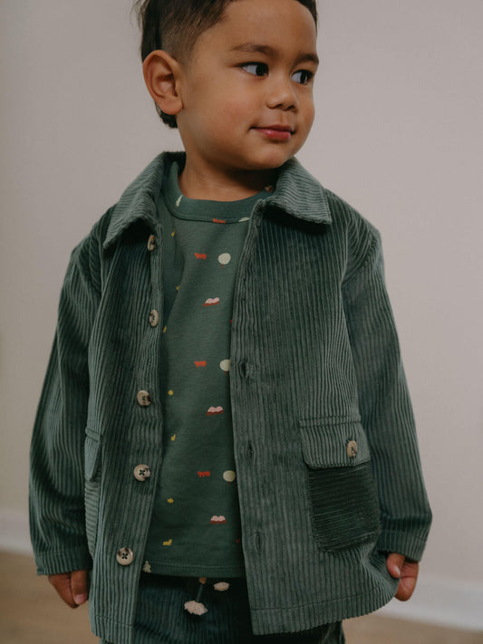 Child wearing a green corduroy jacket and shirt with a plain background