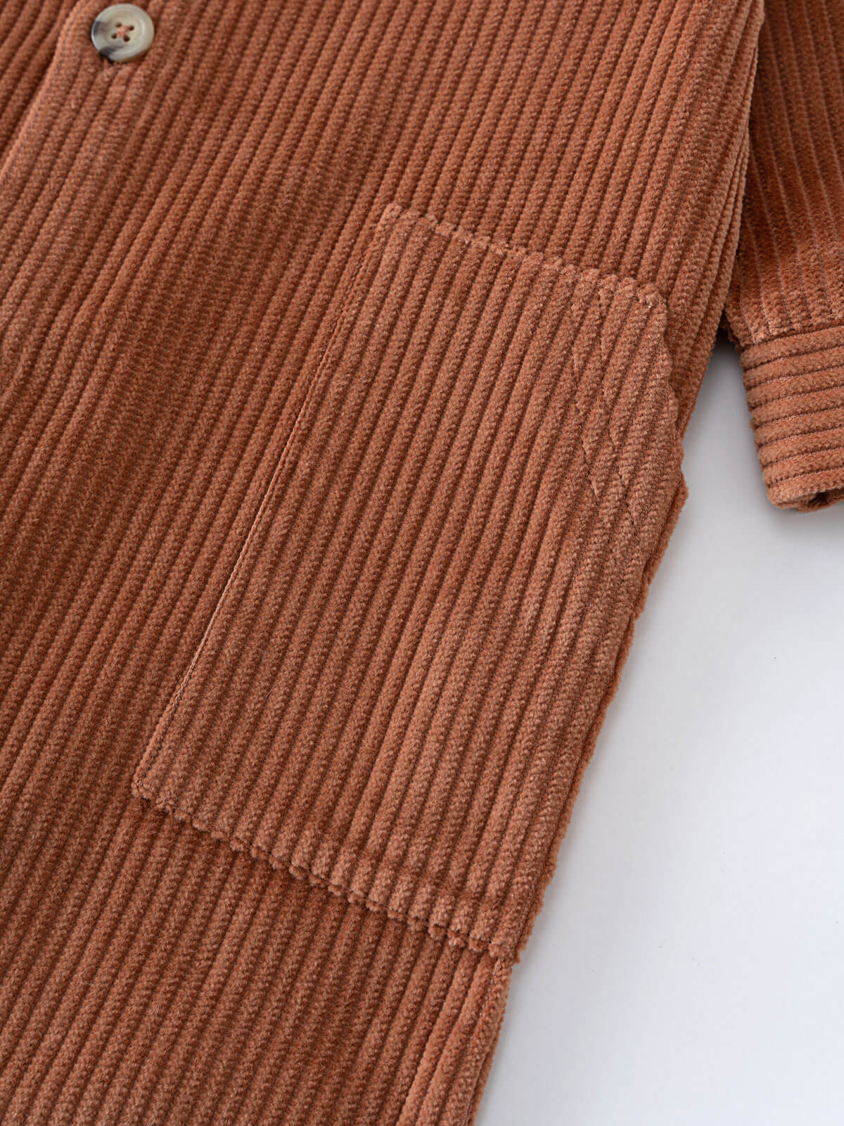 Close-up of rust-colored corduroy fabric with button and chest pocket detail Corduroy Jumpsuit - Russet Baby boy