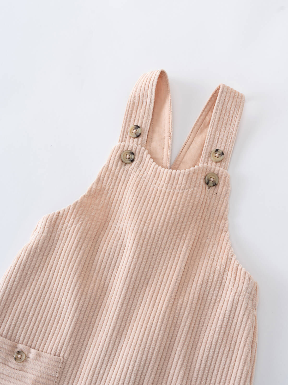 Beige corduroy overalls on a light gray background