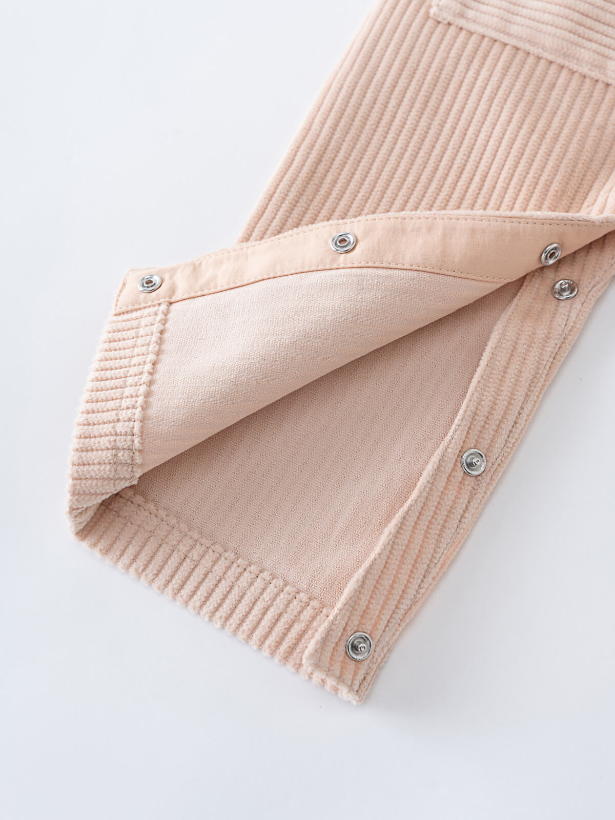 Close-up of a Beige corduroy overalls with button details on a white background