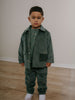 Child wearing a green corduroy outfit standing on a wooden floor. Corduroy Pants - Balsam Girls and Boys