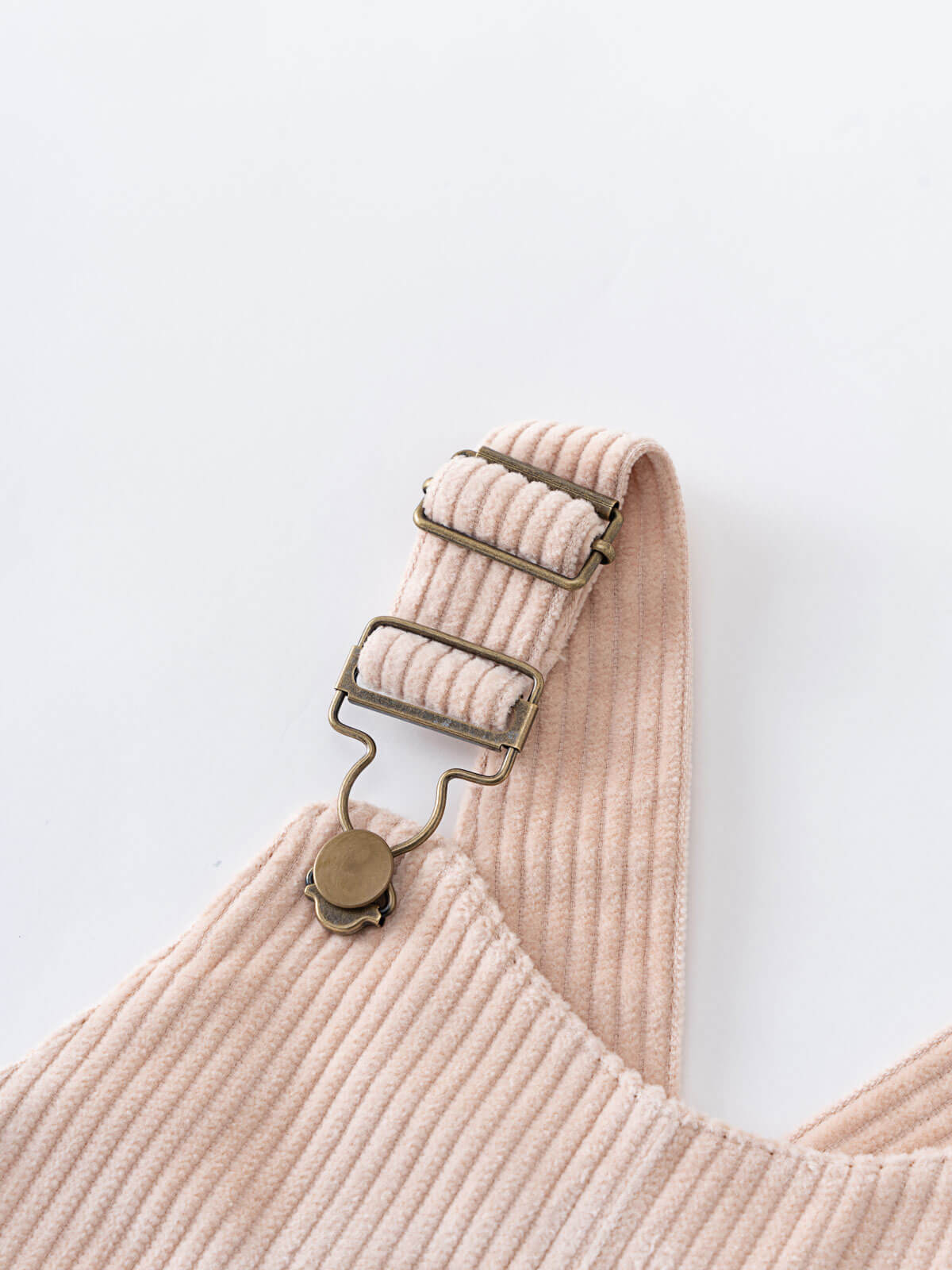 Close-up of a beige corduroy pinafore dress with a brass clasp on a white background Corduroy Pinafore Dress - Clay Girls