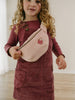 Child wearing a maroon dress holding a beige bag with a bird design. Crossbody Bag - Dove Girls