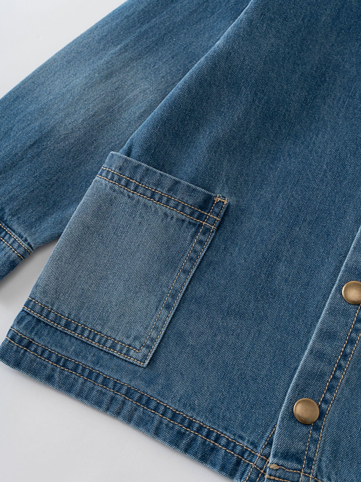 Close-up of a blue denim jacket with a pocket and button details on a light gray background Denim Jacket - Blue Denim Girls and Boys