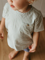Child wearing a striped shirt with a pocket on a neutral background
