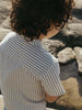 Child wearing a striped shirt standing near water and rocks