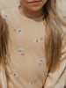 Close-up of a child wearing a beige sweater with shell and starfish patterns.