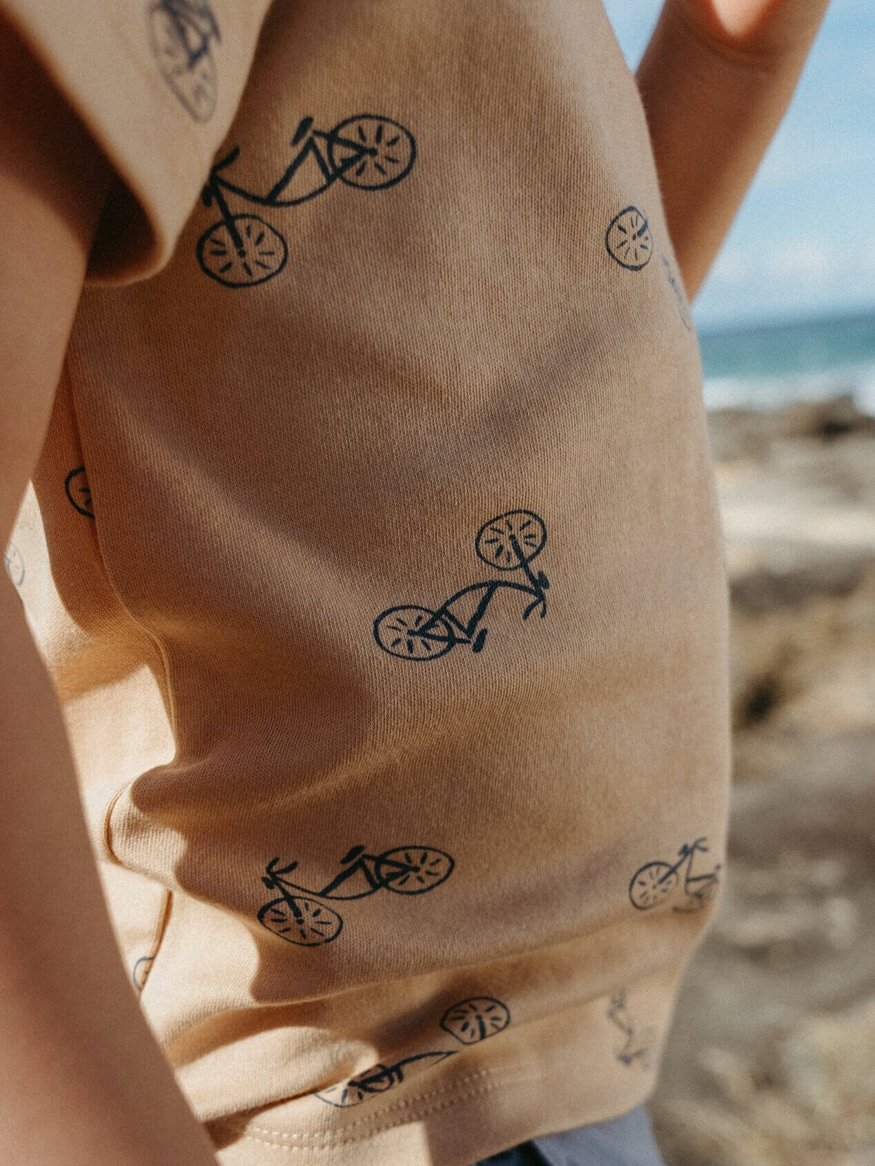 Beige fabric with black bicycle patterns, blurred beach background