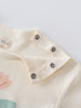 Close-up of cream-colored baby garment shoulder with metal snap buttons Feature Print Short Sleeve Tee - Angel Fish Baby girl