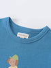 Close-up of a blue t-shirt collar with a small printed graphic below feature print Short Sleeve Tee - Milo Biking Boys