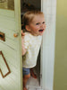 Child peeking out from behind a door with a smile