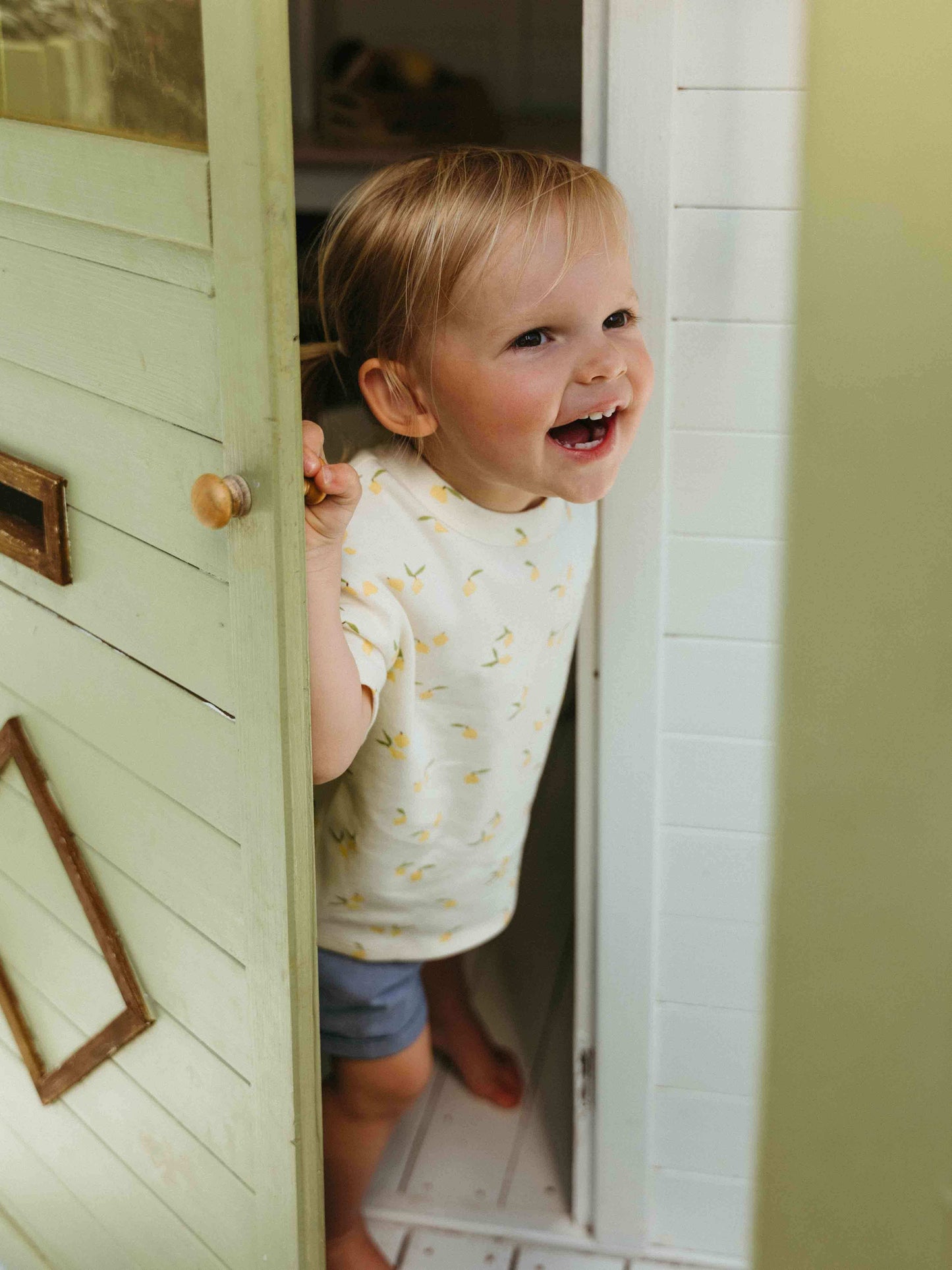 Child peeking out from behind a door with a smile