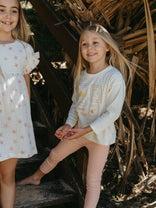 Two young girls standing outdoors with a natural background
