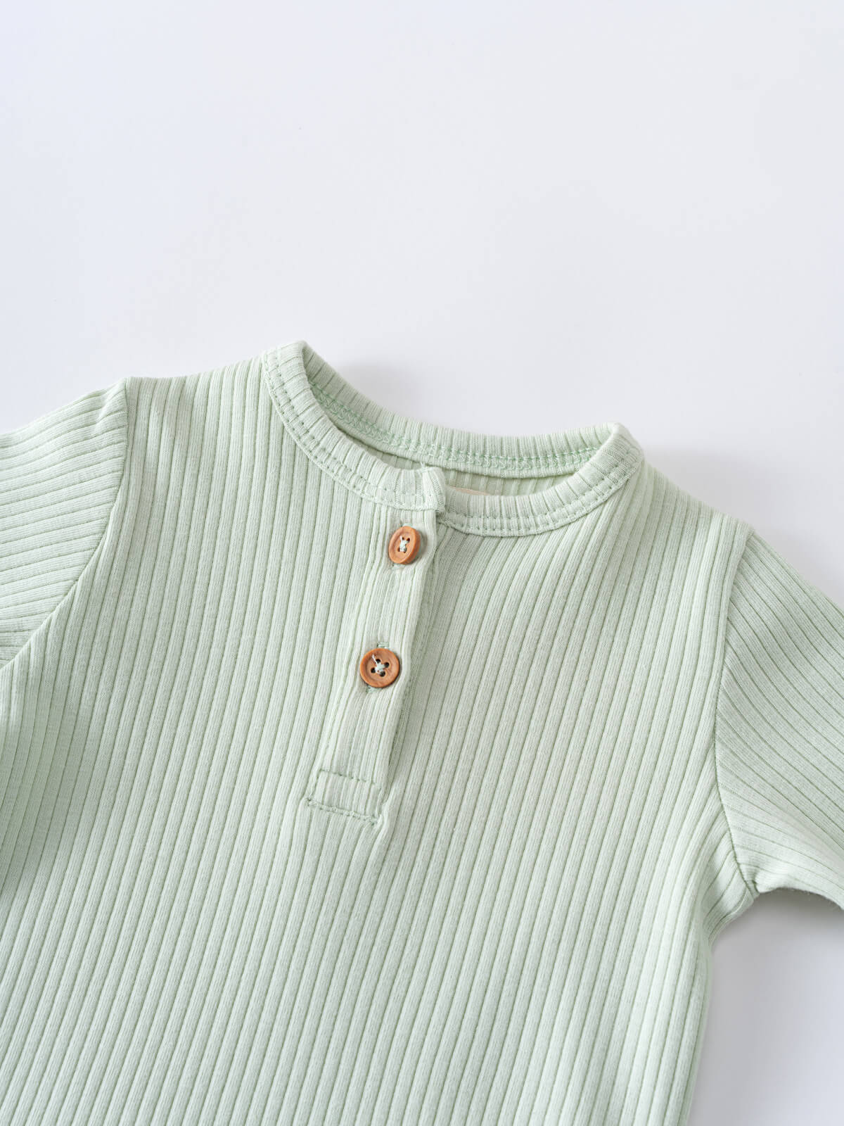 Close-up of a light green ribbed bodysuit with wooden buttons Henley Short Sleeve Bodysuit - Matcha Baby boy